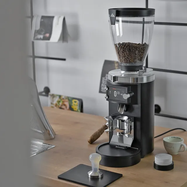 Mahlkönig E65S GbW on a wooden table with a tamper